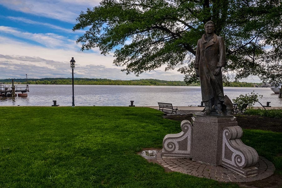 An old statue by the water on a bright day, adding a touch of history to the scenic waterfront