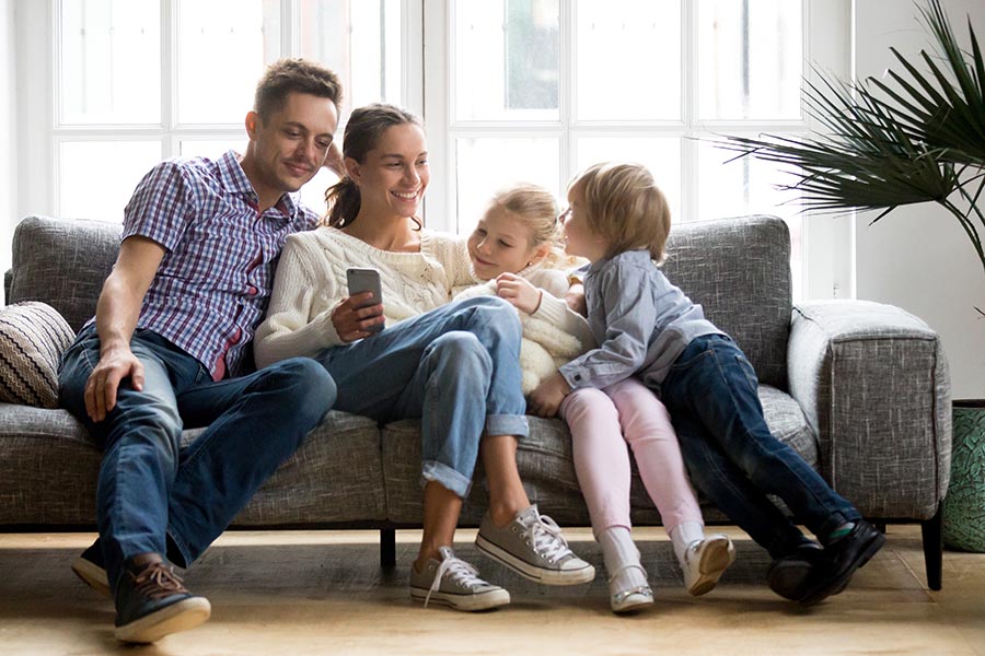 Blog - Young Family Sitting Close On Their Sofa Using a Smartphone